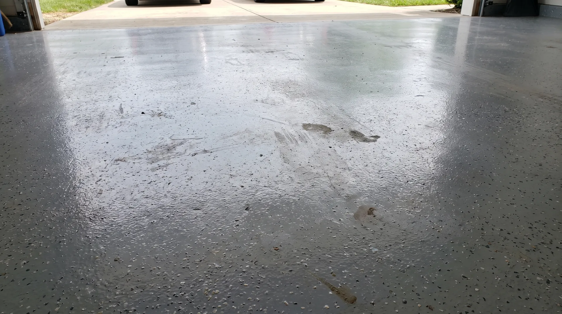 Worn epoxy floor coating showing traffic wear patterns in a San Antonio garage, illustrating epoxy floor coating lifespan