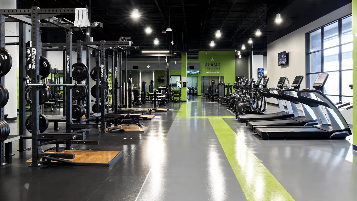 Modern commercial gym in San Antonio with glossy seamless epoxy floor, weight racks, treadmills, and color-zoned floor striping